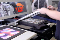 A man is operating a machine that prints clothes